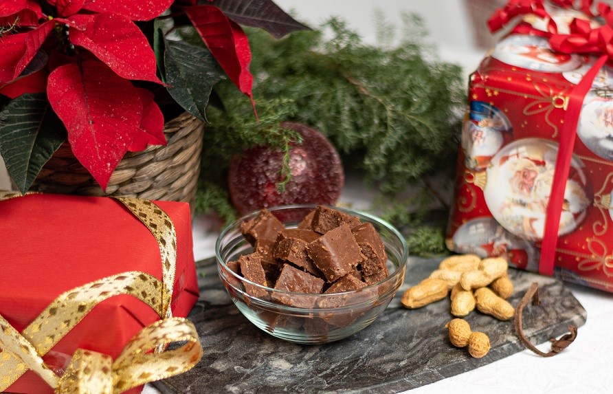 Julefudge der ligger i en skl omringet af gaver og julepynt.