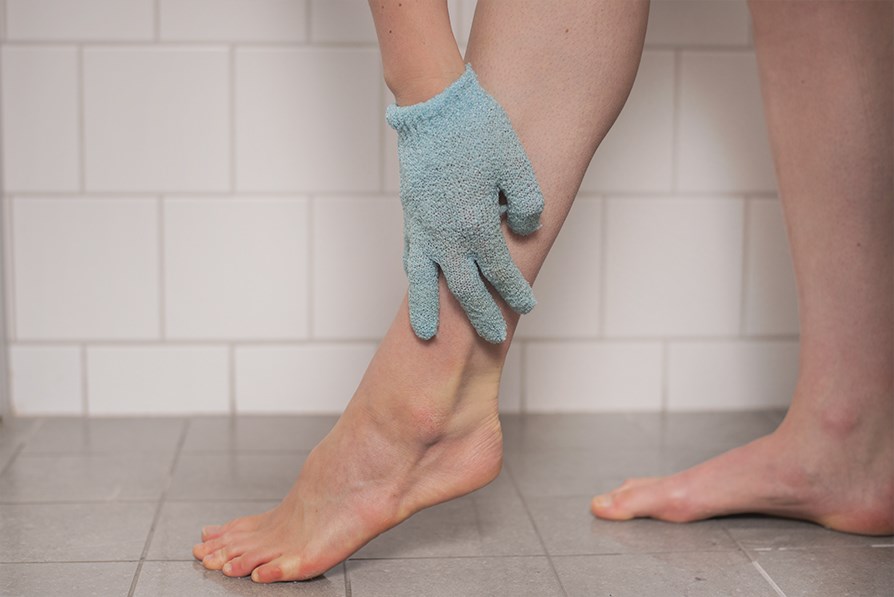 Hånd med skrubbehandske, der peeler et ben Hånd med skrubbehandske, der peeler et ben