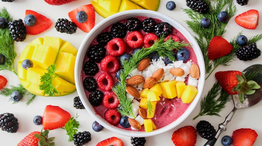 En lyserd smoothie bowl fyldt med diverse antiinflammatoriske ingredienser, som ndder og frugt.