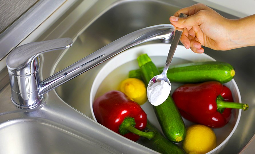 En sk�l med gr�ntsager og en h�nd, der holder en teske med natron