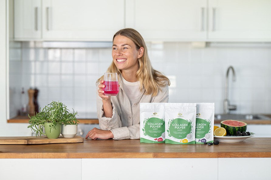 En kvinde st�r foran Healthwell Collagen Pulver Marint.
