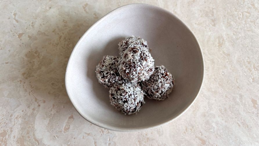 En skl med dadelkugler str p et bord klar til servering.