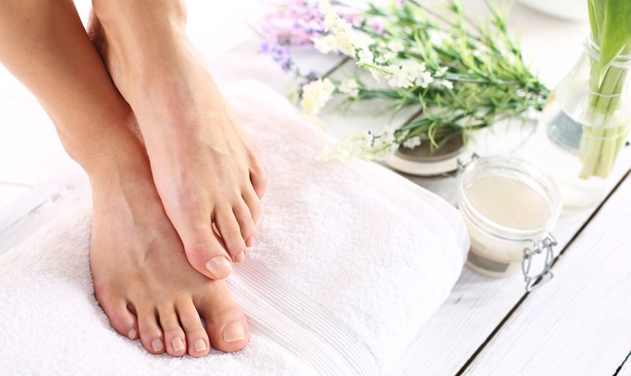 Et par fdder er p et hndklde ved siden af et glas med en hjemmelavet fodscrub.