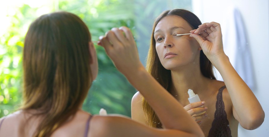 Kvinde bruger vatpind til at p�f�re �jenvippeserum p� vipperne.