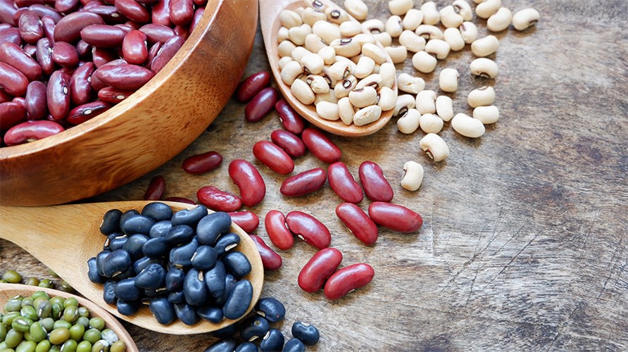 Forskellige slags b�nner anrettet p� tallerkener og tr�skeer p� et tr�bord.