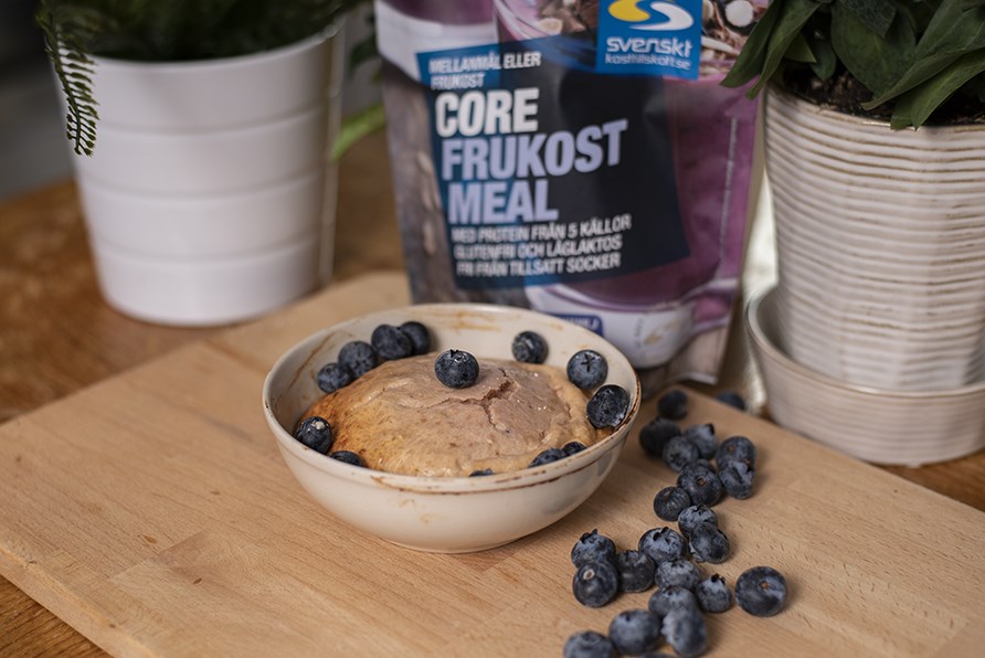 En sk�l med ovnbagt gr�d med friske bl�b�r st�r p� et bord.