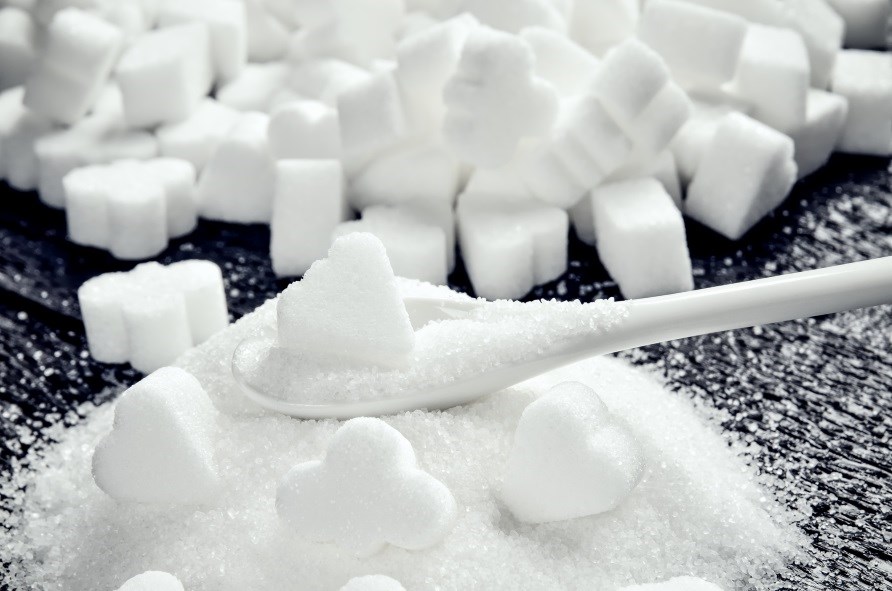 En bunke af sukker med sukkerknalder og en ske. En bunke af sukker med sukkerknalder og en ske.