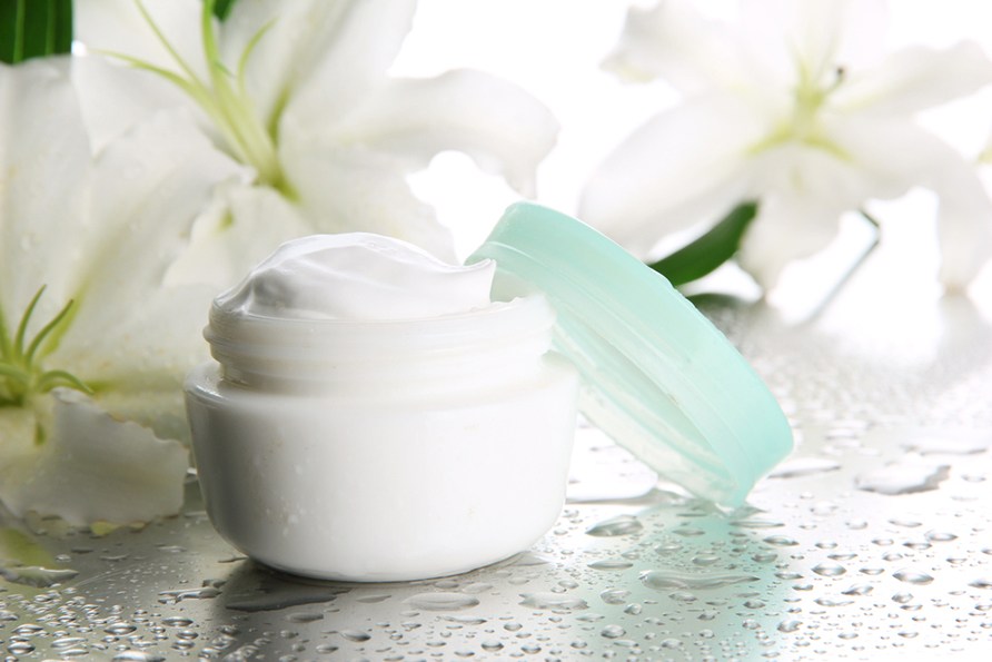 Krukke med hudcreme og smukke liljer i baggrunden.