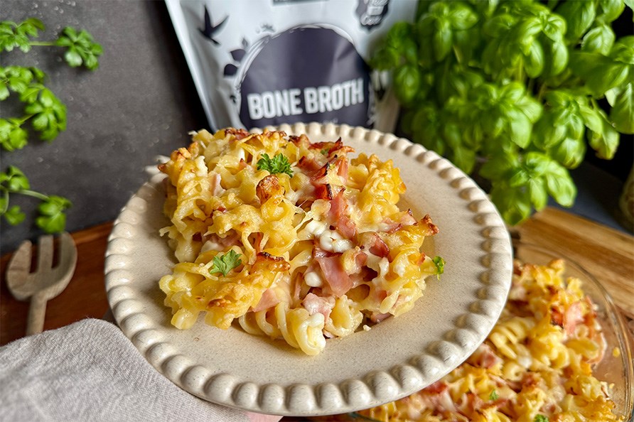 M�ltid med Kalorismarts pastagratin, Healthwell Benbuljong Pulver Gr�sbetat og basilikum placeret p� et k�kkenbord.