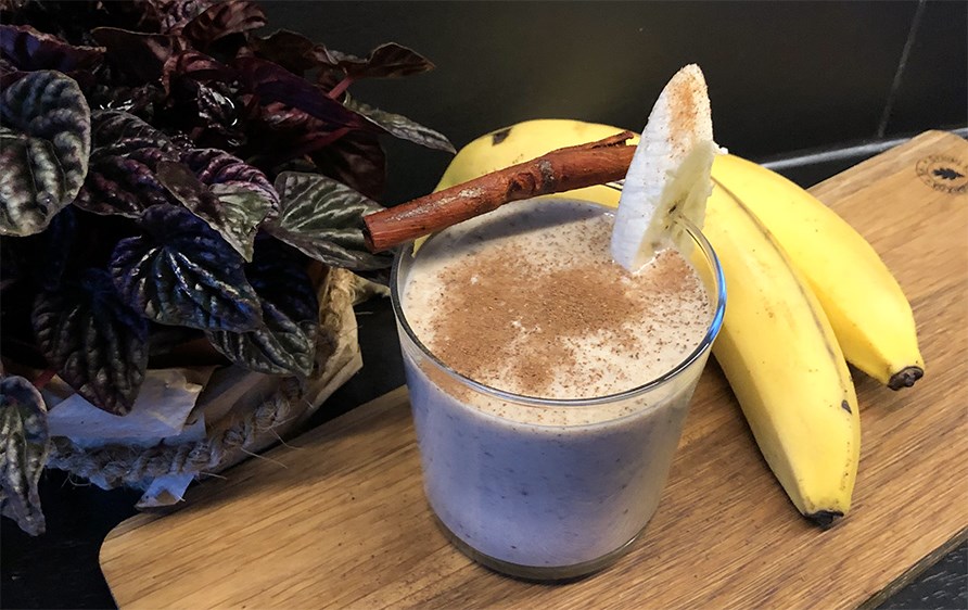 Et glas fyldt med kanelsnegl smoothie str p et bord.