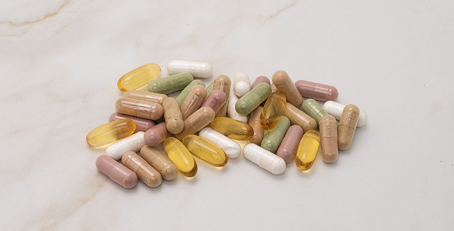 En bunke kapsler fra kosttilskud i forskellige farver