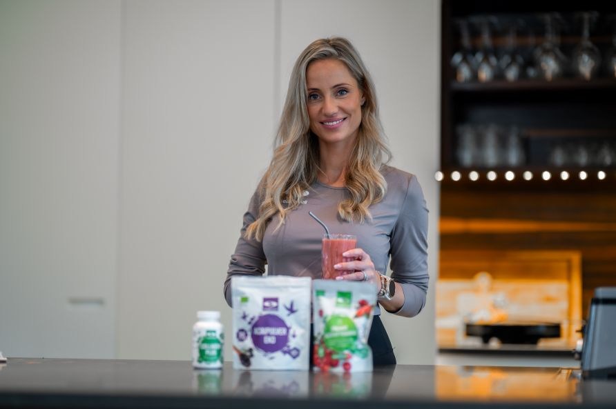 Lea Kessler står i et køkken, hvor hun holder en smoothie, foran produkter fra Healthwell. Lea Kessler står i et køkken, hvor hun holder en smoothie, foran produkter fra Healthwell.