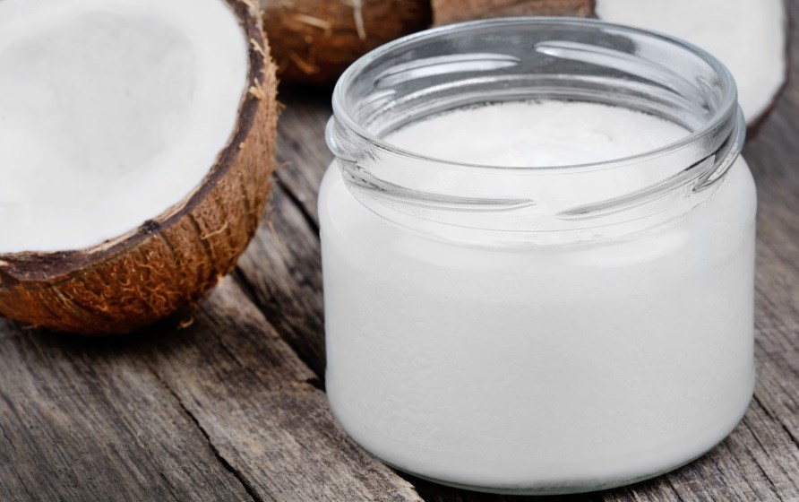 Kokosolie i glasbeholder med en halv kokosnød ved siden af. Kokosolie i glasbeholder med en halv kokosnød ved siden af.