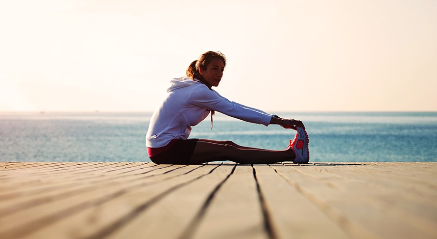 En pige sidder p� en bro og str�kker ud.