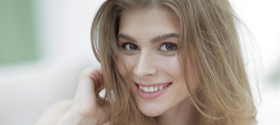 En kvinde med flot hud og hr kigger direkte p kameraet.
