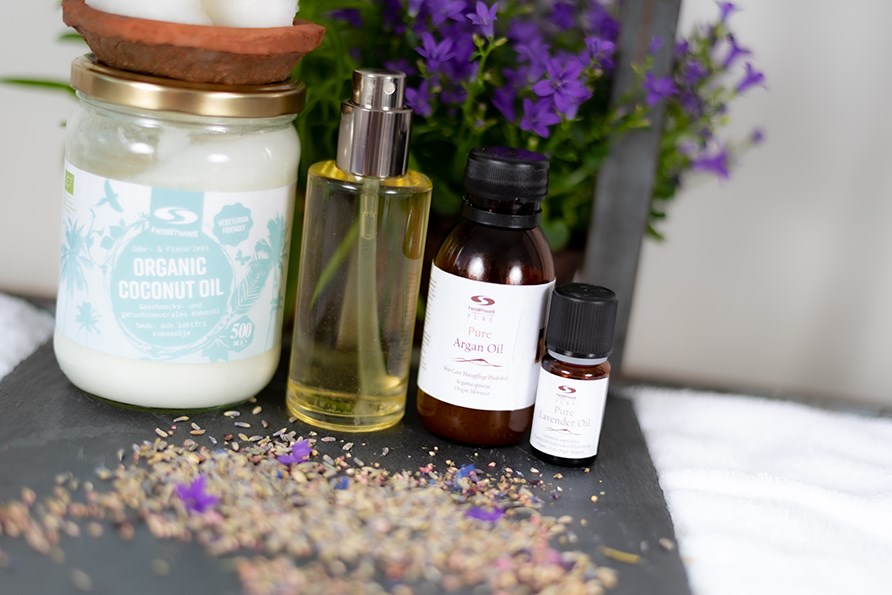 Kokosolie, kropsolie, arganolie og ren lavendelolie str p en bakke.