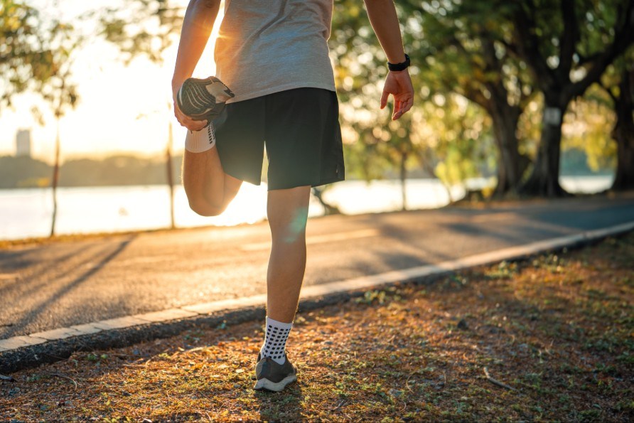 En mand strkker lrets muskel under en lbetur.