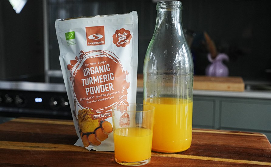 Sofia St�hls ingef�rshots i en kande og i et glas samt Healthwell Gurkemeje Pulver �KO stillet frem p� et k�kkenbord.