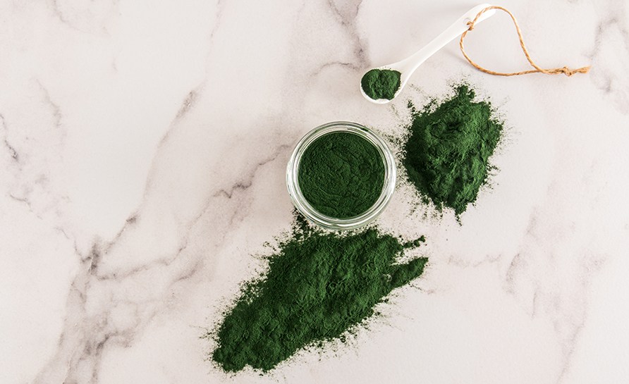 Spirulina pulver ligger i en skl, en ske og p bordet.