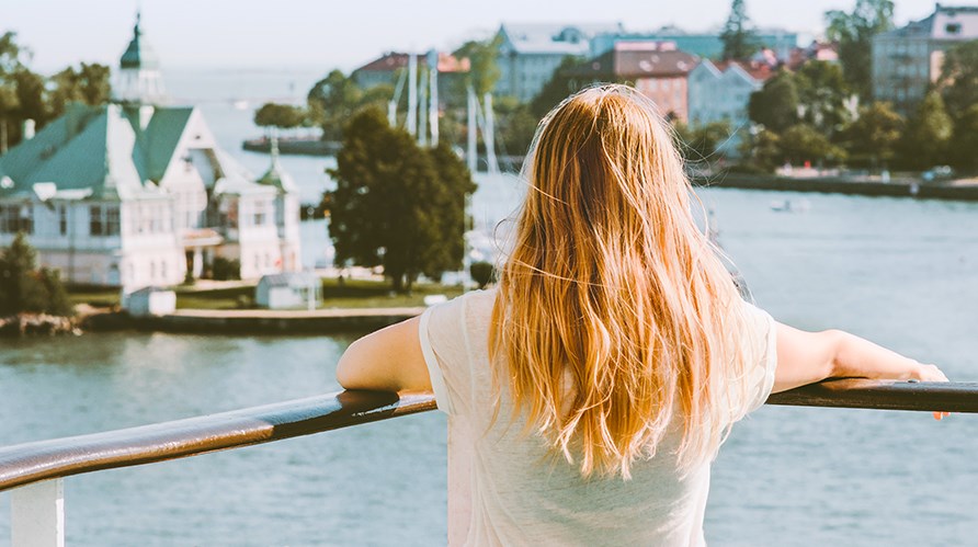 En kvinde med mellem langt hår står med ryggen til og kigger ud over en by. En kvinde med mellem langt hår står med ryggen til og kigger ud over en by.