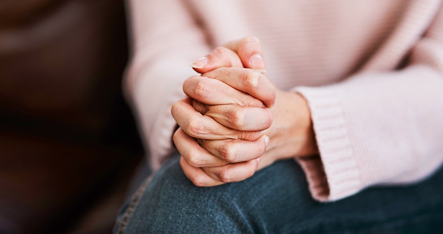 En kvinde holder sidder med hendes h�nder samlet i sit sk�d.