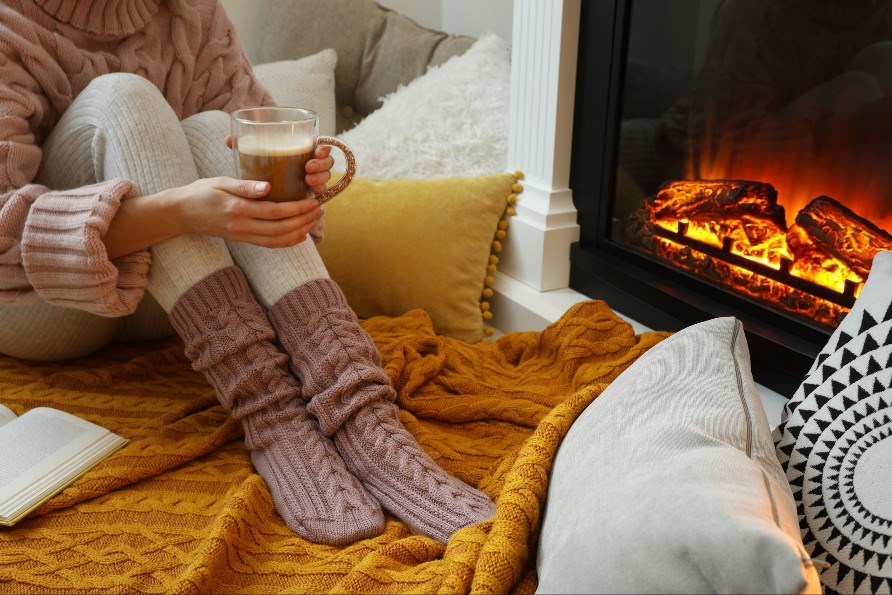En person drikker en kop te foran pejsen.