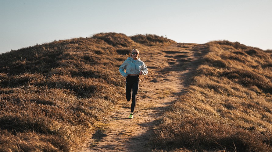 En kvinde, der lber ned ad en sti p et bjerg.